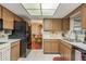 Galley kitchen with wood cabinets, black appliances and tile floor at 14315 Arbor Hills Rd, Tampa, FL 33625