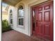 Welcoming front entry featuring a red door and arched windows at 18442 New London Ave, Land O Lakes, FL 34638