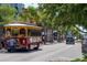 A charming street scene with a vintage trolley, shops, and parked cars at 204 Sky Loch W Dr, Dunedin, FL 34698