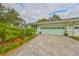 House exterior featuring a light green garage door, paved driveway, and well-manicured landscaping at 2510 Lambdin Dr, Sun City Center, FL 33573