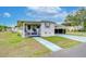 Side view of a white mobile home with a covered porch and landscaping at 37350 Tropical Dr, Zephyrhills, FL 33541