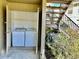 Enclosed outdoor laundry room with white washer and dryer, adjacent to stairs and landscaping at 4208 Winding Moss Trl # 102, Tampa, FL 33613