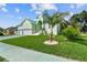 Attractive light green house with a three-car garage, palm tree, and manicured lawn at 711 Eagle Ln, Apollo Beach, FL 33572