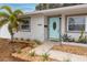 Welcoming front entrance featuring a teal door and attractive landscaping at 7449 16Th N St, St Petersburg, FL 33702