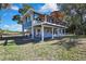 Elevated blue home with deck, carport, and surrounding lush landscaping at 10581 Pine Island Dr, Weeki Wachee, FL 34607