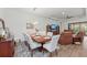 Open concept dining room with a wooden table, white chairs and views into living room at 10804 Wicker Park Pl, Palmetto, FL 34221