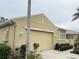 Exterior view of a two-car garage with beige paint, an arched roof, and neatly trimmed bushes at 2124 Sifield Greens Way # 11, Sun City Center, FL 33573