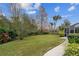 Landscaped backyard with lush greenery, a spacious lawn, and a screened enclosure at 2126 Larchwood Ct, Trinity, FL 34655