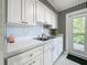 White kitchen with stainless steel appliances and black and white striped wallpaper at 229 Lime S Cir, Dunedin, FL 34698