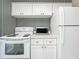 White kitchen with stainless steel appliances and black and white striped wallpaper at 229 Lime S Cir, Dunedin, FL 34698