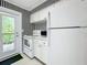 White kitchen with stainless steel appliances and black and white striped wallpaper at 229 Lime S Cir, Dunedin, FL 34698