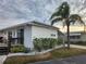 White single-wide manufactured home with deck, landscaping, and palm tree at 236 Carol Dr # 236, Seminole, FL 33772