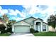 Single-story house with a green exterior, two-car garage, and landscaped lawn at 25237 Seven Rivers Cir, Land O Lakes, FL 34639