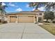 Two-story house with beige exterior, three-car garage, and landscaped yard at 4381 Caliquen Dr, Brooksville, FL 34604