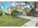 Two-story yellow house with gray garage door and well manicured lawn at 5608 Rockfield Loop, Valrico, FL 33596