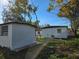 Backyard view of two white buildings, surrounded by trees and partially cleared land at 6413 N 48Th St, Tampa, FL 33610