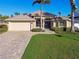 Beautiful single-story home with a lush green lawn, a brick driveway, and a two-car garage at 924 Landmark S Cir, Tierra Verde, FL 33715