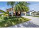 Tan house with palm trees, landscaping, and a black garage door at 11810 Winterset Cove Dr, Riverview, FL 33579