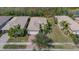 Aerial view showcasing a well-maintained home with manicured lawn, brick driveway, and beautiful tile roof at 16127 Cape Coral Dr, Wimauma, FL 33598