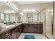 Spacious bathroom featuring dual sinks, dark wood cabinets, and a glass-enclosed shower at 16127 Cape Coral Dr, Wimauma, FL 33598