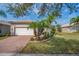 Charming home featuring a brick driveway, manicured lawn, tropical landscaping, and an attached two-car garage at 16127 Cape Coral Dr, Wimauma, FL 33598