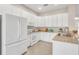 Bright kitchen featuring white cabinetry, stainless steel appliances, and tile flooring at 16127 Cape Coral Dr, Wimauma, FL 33598