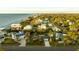 Aerial view showcasing a neighborhood's waterfront homes, lush greenery, and calm waters at 608 Florida Blvd, Crystal Beach, FL 34681