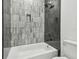 Clean bathroom with gray and dark tile shower and white bathtub at 7711 N Orleans Ave, Tampa, FL 33604