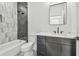 Modern bathroom with gray tile shower, white bathtub, and dark vanity at 7711 N Orleans Ave, Tampa, FL 33604