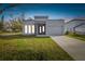 Modern single-story home with gray exterior, stone accents, and attached garage at 7711 N Orleans Ave, Tampa, FL 33604