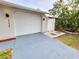 White garage door with a side gate and a new driveway at 9334 Ledgestone Ln, Port Richey, FL 34668