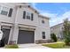 Two-story townhome with gray siding, dark gray garage door, and landscaped yard at 9642 Sweetwell Pl, Riverview, FL 33569