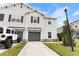 Two-story townhome with gray siding, dark gray garage door, and landscaped yard at 9642 Sweetwell Pl, Riverview, FL 33569