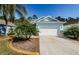 Light blue house with white garage door, palm trees, and landscaped yard at 11036 Paradise Point Way, New Port Richey, FL 34654