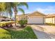 Tan house with white garage door, palm trees, and landscaped yard at 15767 Crystal Waters Dr, Wimauma, FL 33598