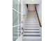 Modern white staircase with dark wood railing and glass door at 160 174Th Terrace E Dr # B, Redington Shores, FL 33708