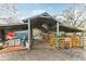 Image features a horse stall or pen area with weathered wooden planks and a metal roof offering shelter on a gravel surface at 3009 Jim Johnson Rd, Plant City, FL 33566