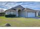 Front view of a single story house with a white garage door at 6932 Oakcrest Way, Zephyrhills, FL 33542