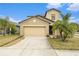 Two-story house with tan exterior, two-car garage, and palm trees at 7610 Blue Iris Ln, Tampa, FL 33619