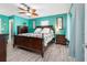 Main bedroom with a king-size bed, ceiling fan, and teal walls at 8460 Parkwood Blvd, Seminole, FL 33777