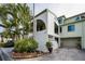 Charming two-story condo with stucco siding, an attached garage, and lush tropical landscaping at 2353 Hanover Dr, Dunedin, FL 34698