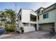 Charming two-story condo with stucco siding, an attached garage, and lush tropical landscaping at 2353 Hanover Dr, Dunedin, FL 34698