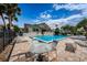 Outdoor pool area with lounge chairs, tables, and palm trees under a blue sky at 2353 Hanover Dr, Dunedin, FL 34698