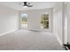 Spacious bedroom with grey carpet, ceiling fan, and large windows at 291 Winchester Way, Palm Harbor, FL 34684