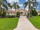 Stunning home exterior with a tile roof, palm trees, and brick driveway at 34303 Sahalee Loop, Dade City, FL 33525