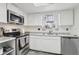 A well-lit kitchen featuring stainless steel appliances, white cabinets, and a granite countertop at 5328 Ridgewell Ct, Tampa, FL 33624