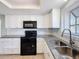 Modern kitchen featuring white cabinets, granite counters, and black appliances at 1116 E Boyer St, Tarpon Springs, FL 34689