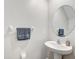 Well-lit half bathroom features pedestal sink, round mirror, and a towel rack at 13456 Marble Sands Ct, Hudson, FL 34669
