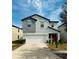 Two story home featuring an attached two car garage, red door, and manicured landscaping at 13456 Marble Sands Ct, Hudson, FL 34669