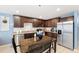 Kitchen with dark brown cabinets, granite counters, stainless steel appliances, and a dining area at 17071 Oval Rum Dr, Wimauma, FL 33598